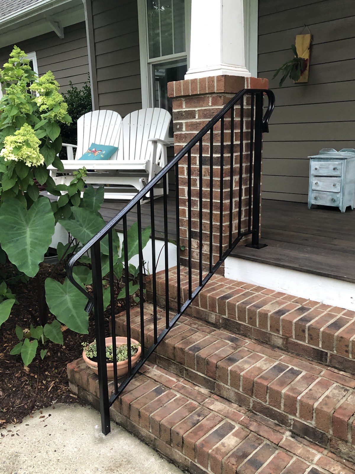 Black ornamental metal handrails along brick porch steps
