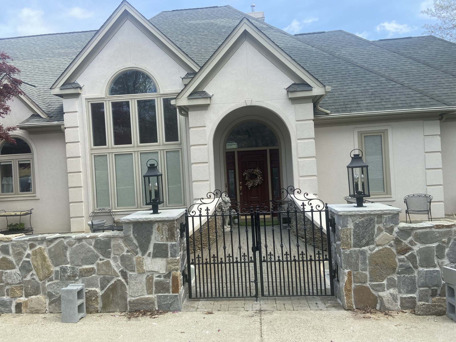 Ornamental iron gates and courtyard railing outside a stone-front home